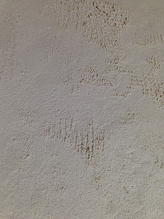 Progettazione e realizzazione di una parete con finitura in terra cruda con intrusioni e pattern superficiali in un’abitazione.