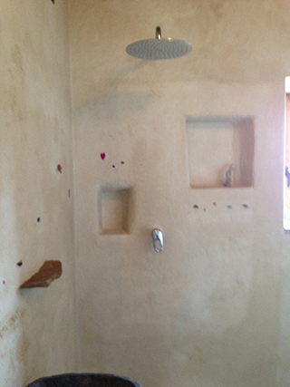 Progettazione e realizzazione di una parete con finitura in terra cruda con intrusioni e pattern superficiali in un’abitazione.