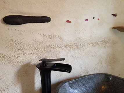 Progettazione e realizzazione di una parete con finitura in terra cruda con intrusioni e pattern superficiali in un’abitazione.
