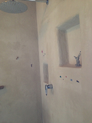 Progettazione e realizzazione di una parete con finitura in terra cruda con intrusioni e pattern superficiali in un’abitazione.