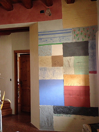 Progettazione e realizzazione di una parete con finitura in terra cruda con intrusioni e pattern superficiali in un’abitazione. Patchwork di Terra